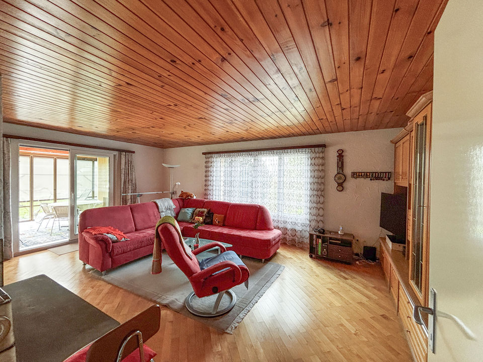 Wohnzimmer mit Holzdecke und roter Eckcouch