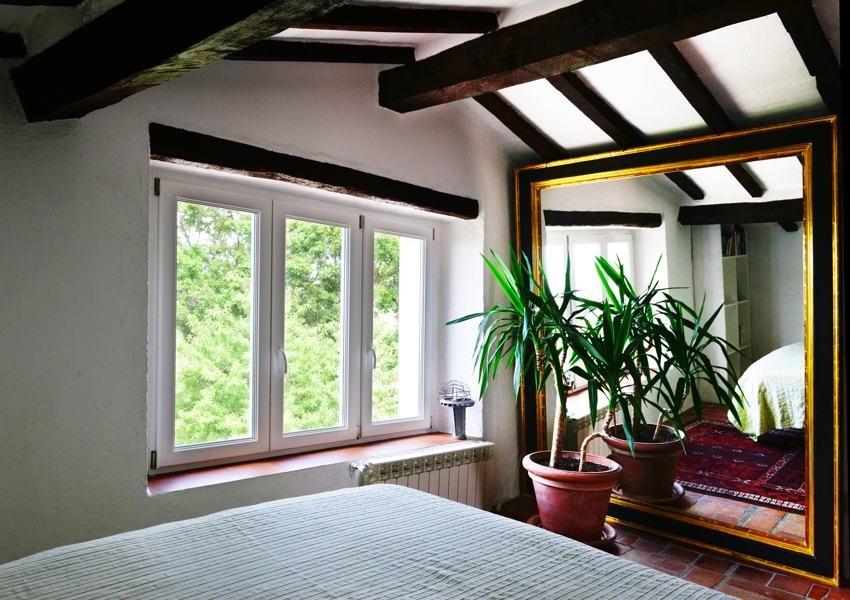 Schlafzimmer mit sichtbaren Holzbalken und großem Spiegel