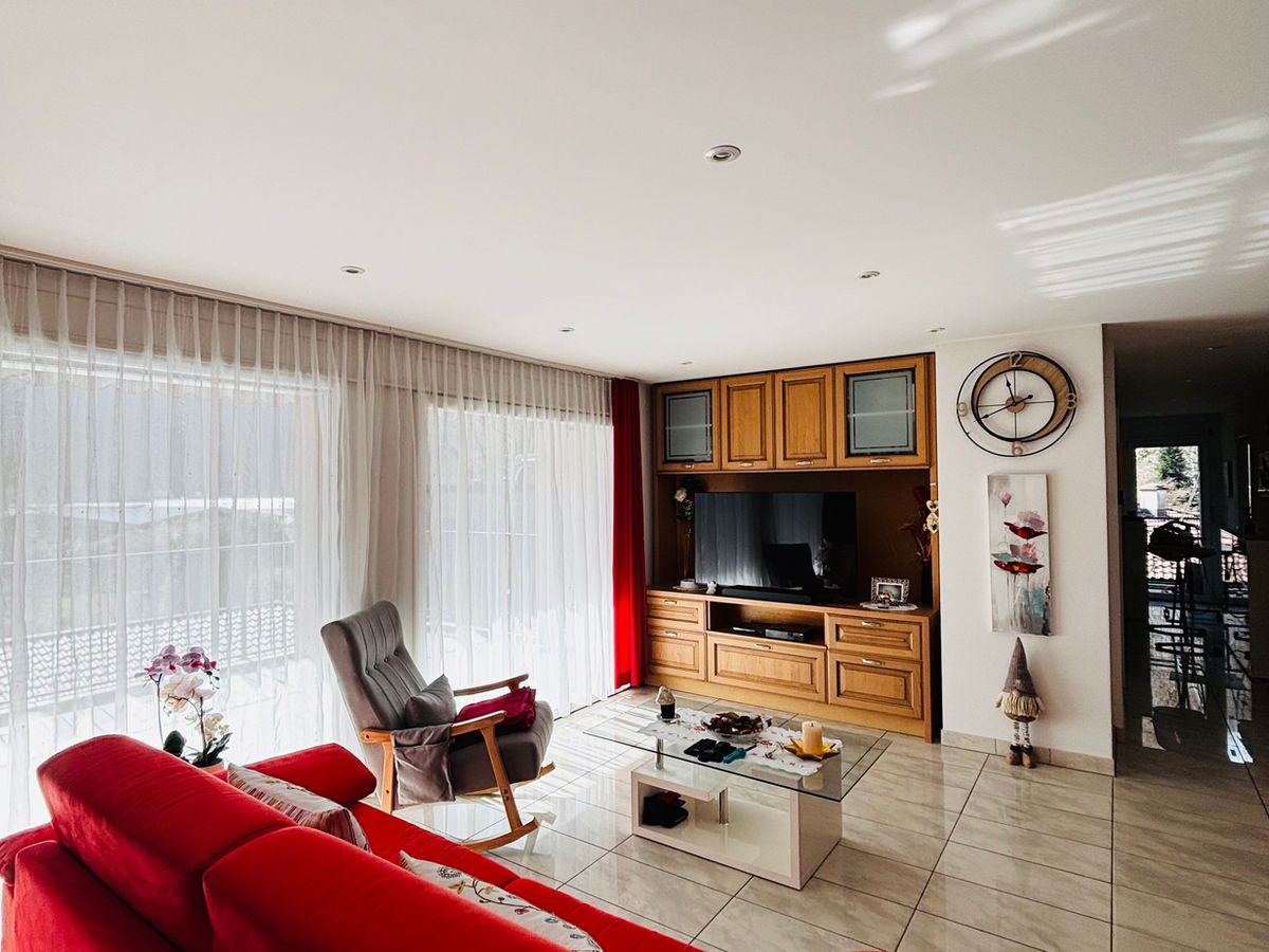 Wohnzimmer mit großer Fensterfront und TV-Wand