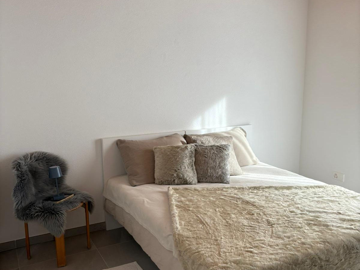 Schlichtes Schlafzimmer mit Bett und Stuhl