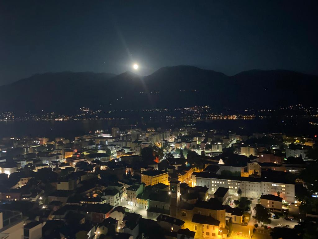Nachtansicht einer Stadt mit Mond über Bergen