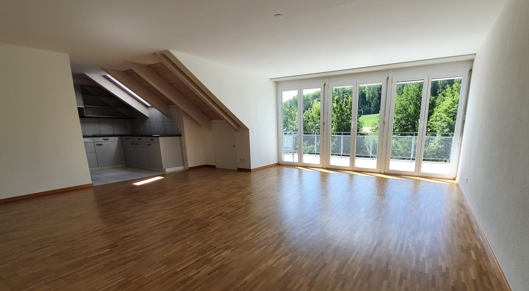 Heller Wohnraum mit Dachschrägen und Balkonblick