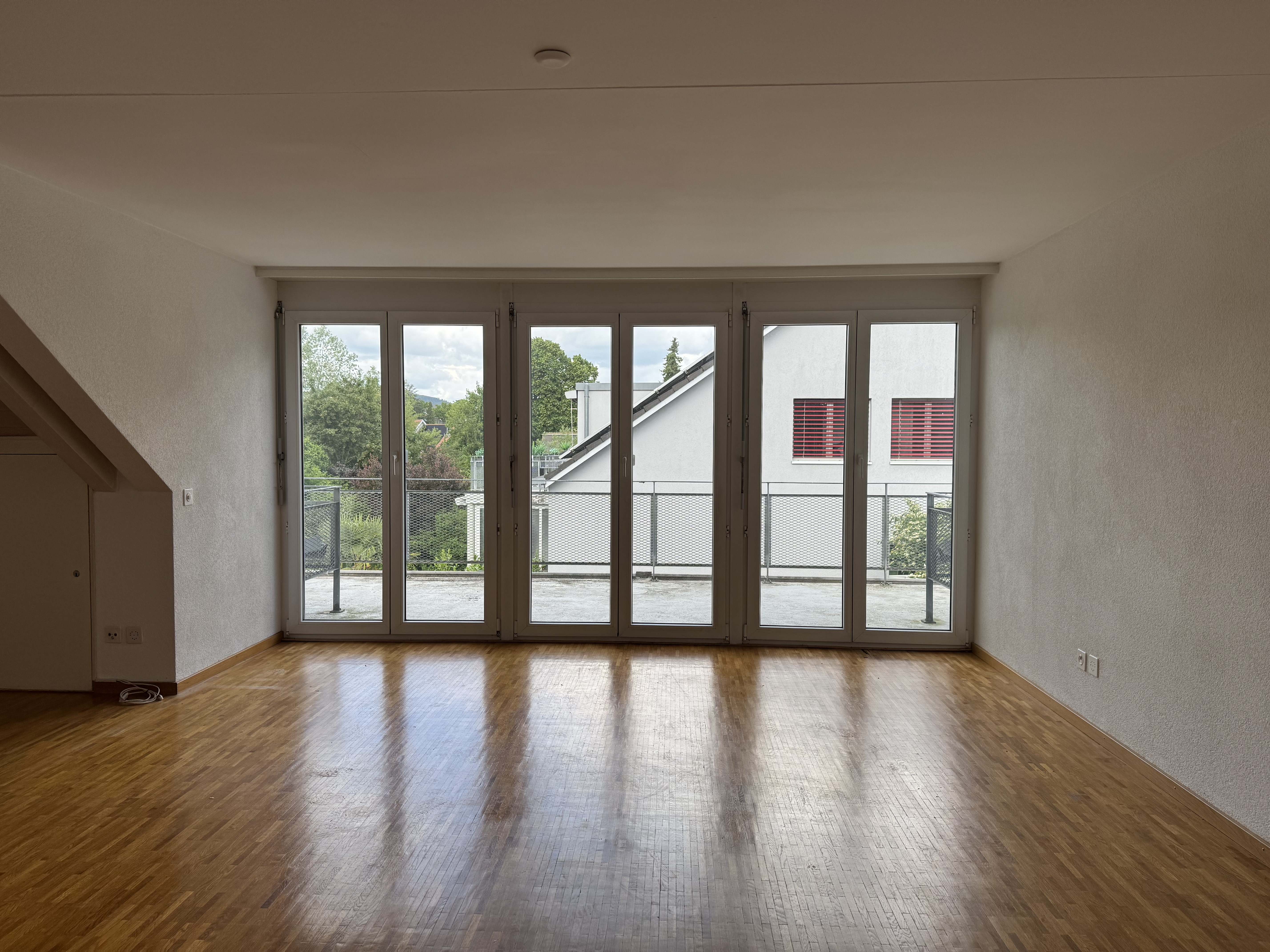 Leerer Dachgeschossraum mit Balkonblick