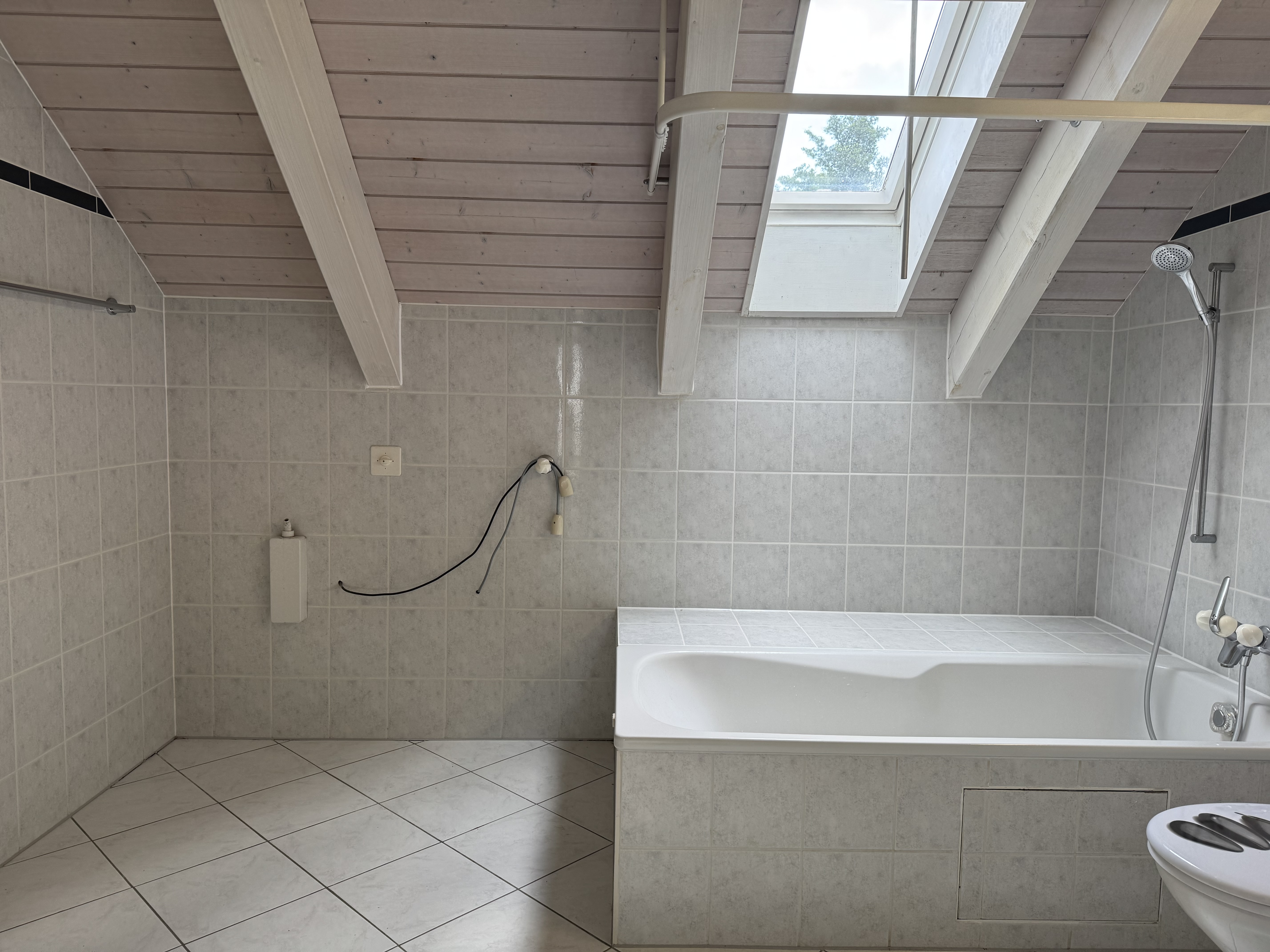 Dachgeschossbad mit Badewanne und Dachfenster