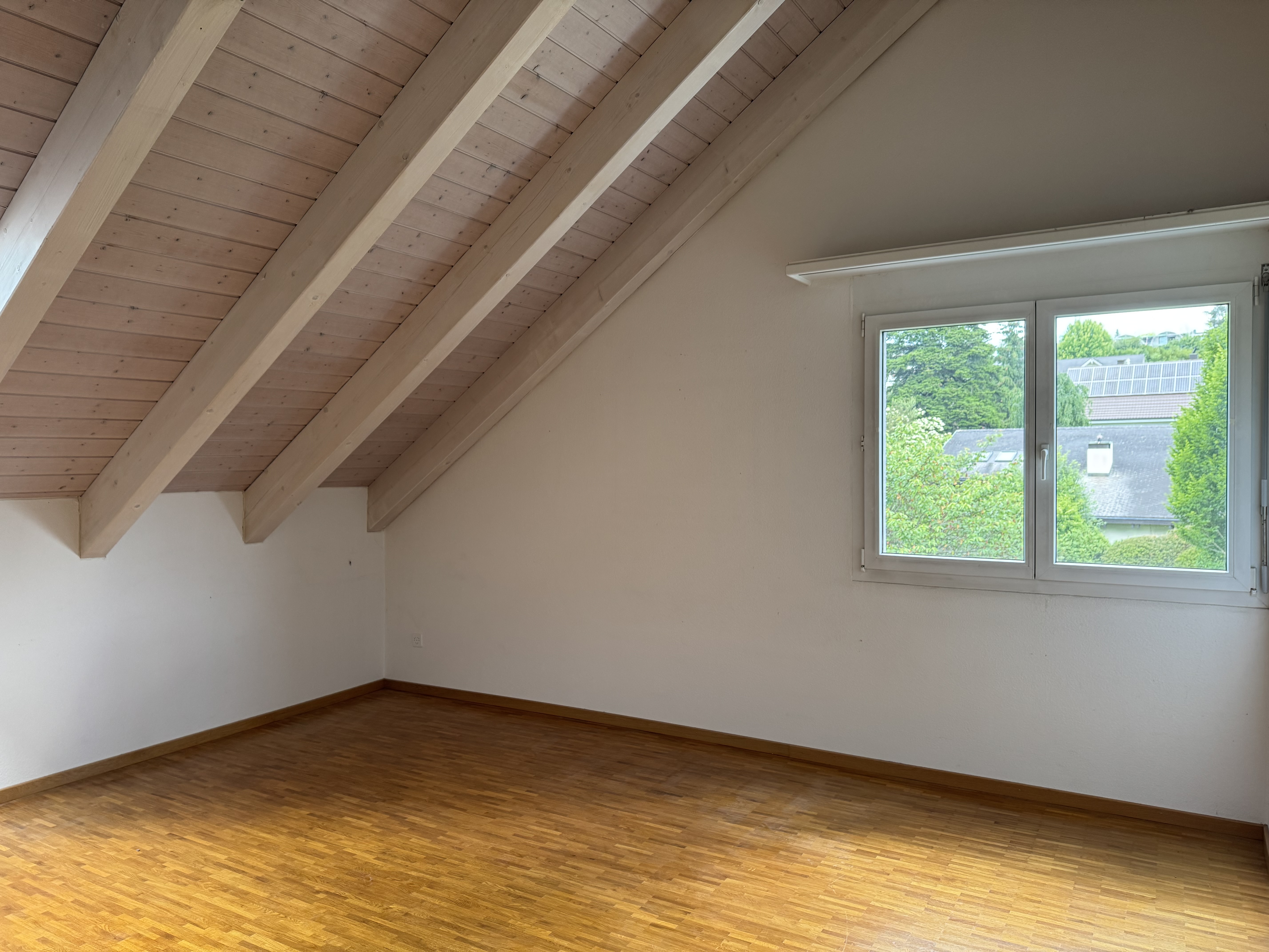 Dachgeschossraum mit Holzdecke und Fenster