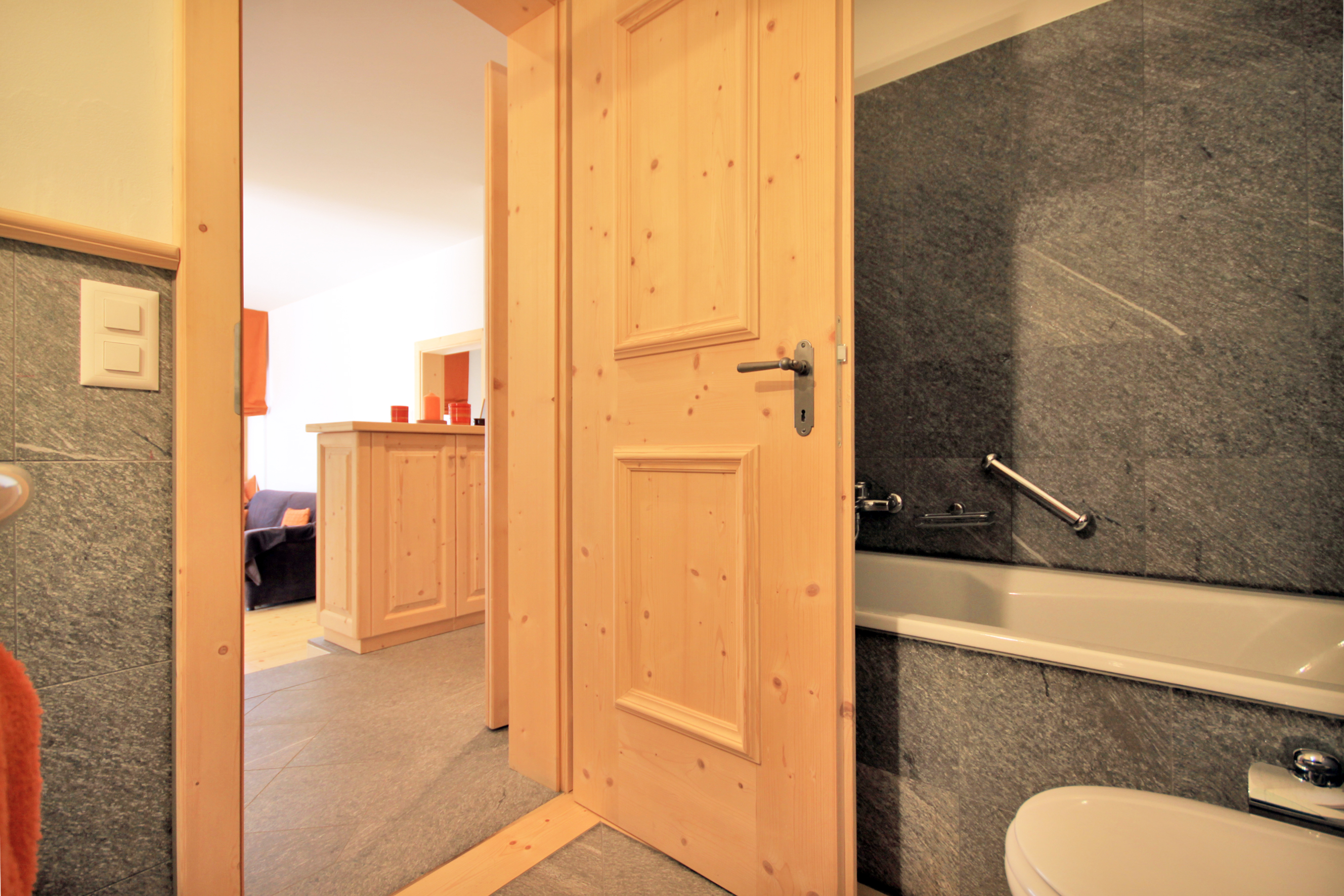 Badezimmer mit Holztür und Natursteinverkleidung