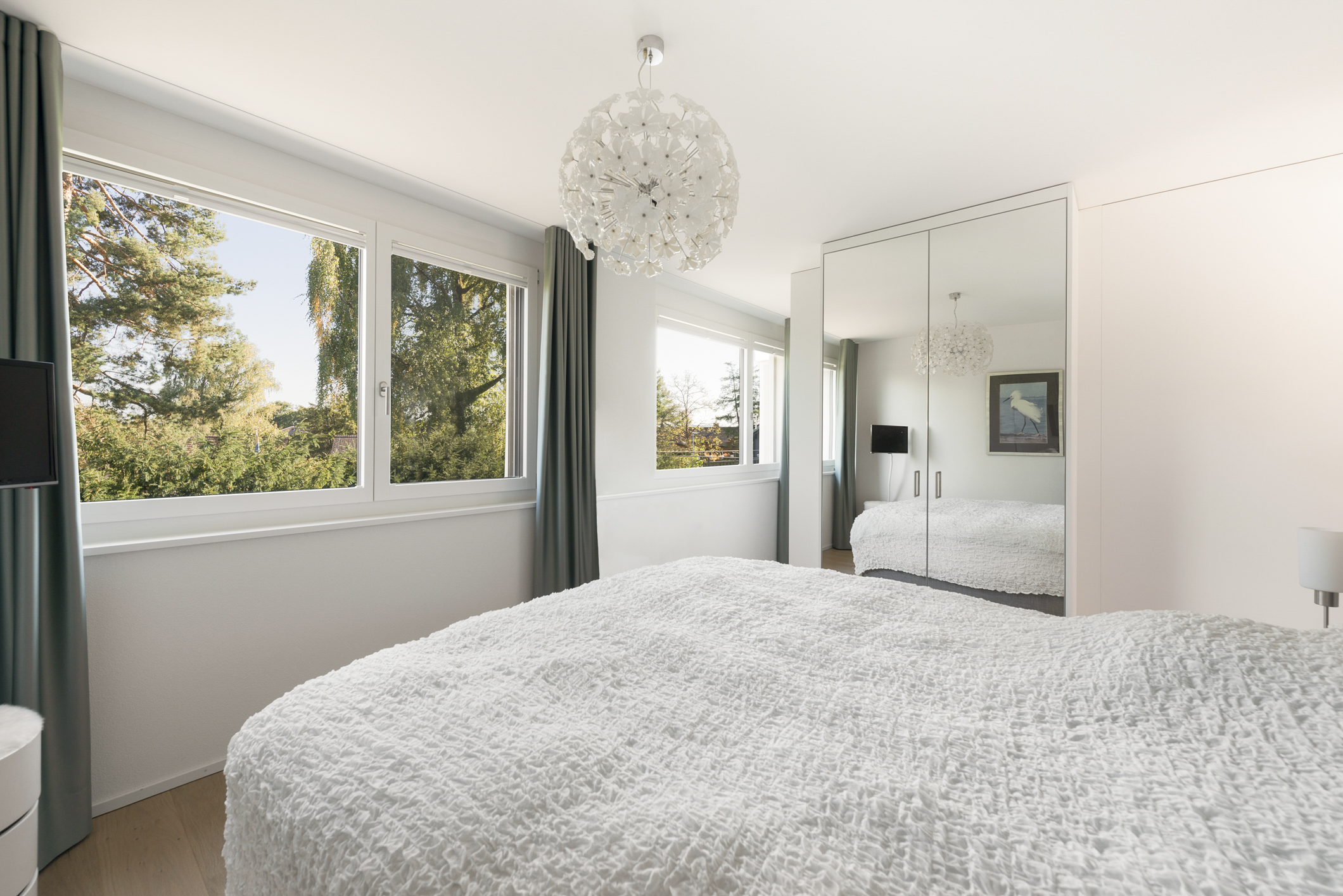 Helles Schlafzimmer mit großen Fenstern und Spiegelkleiderschrank