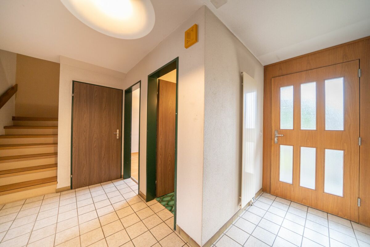 Heller Eingangsbereich mit Treppe und mehreren Holztüren