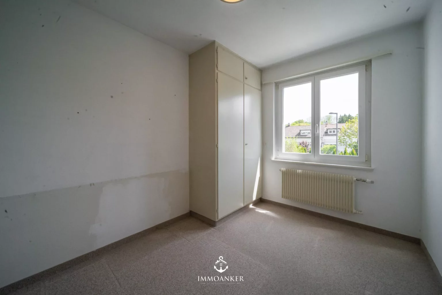 Helles, leeres Zimmer mit Einbauschrank und Fenster