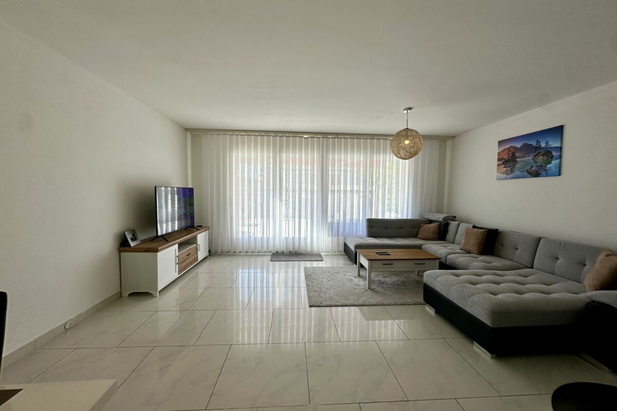 Helles Wohnzimmer mit Ecksofa und großem Fenster