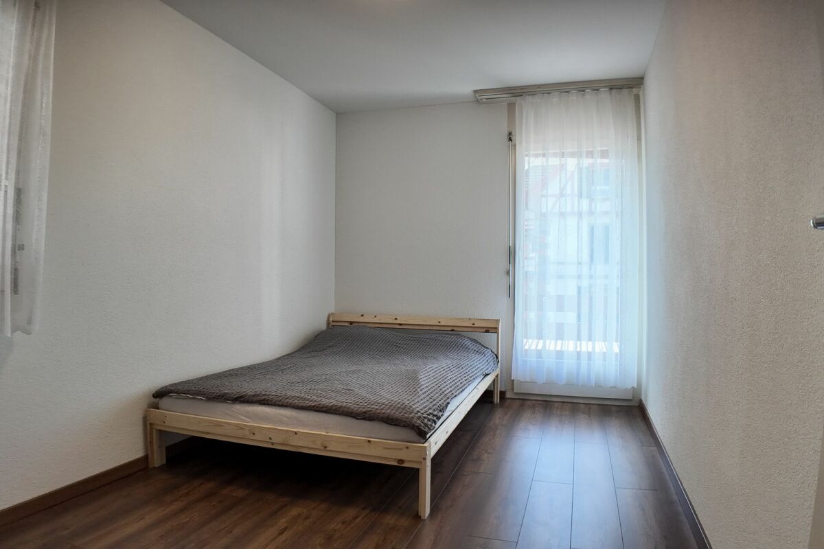 Schlichtes Schlafzimmer mit Einzelbett und Balkonfenster