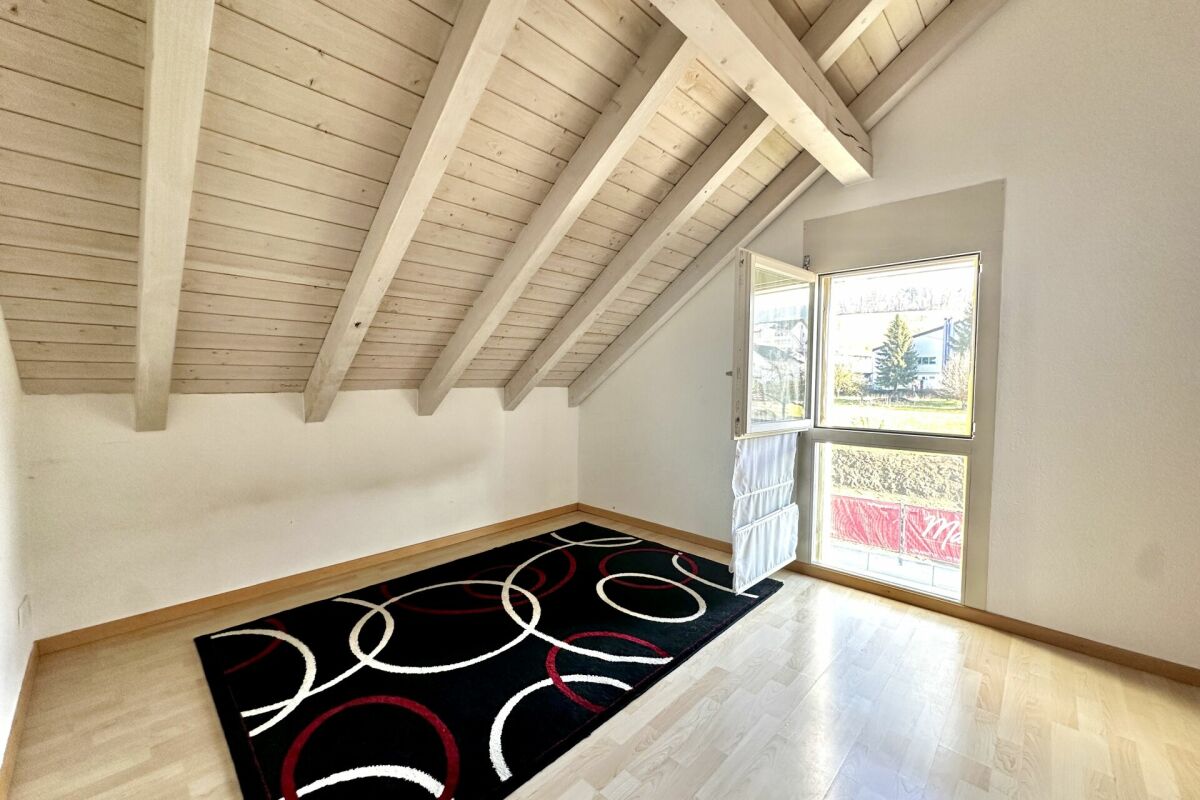 Helles Dachgeschosszimmer mit sichtbaren Holzbalken