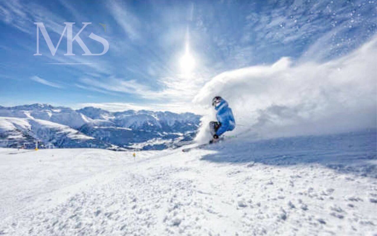 Skipiste mit Snowboarder vor alpiner Bergkulisse