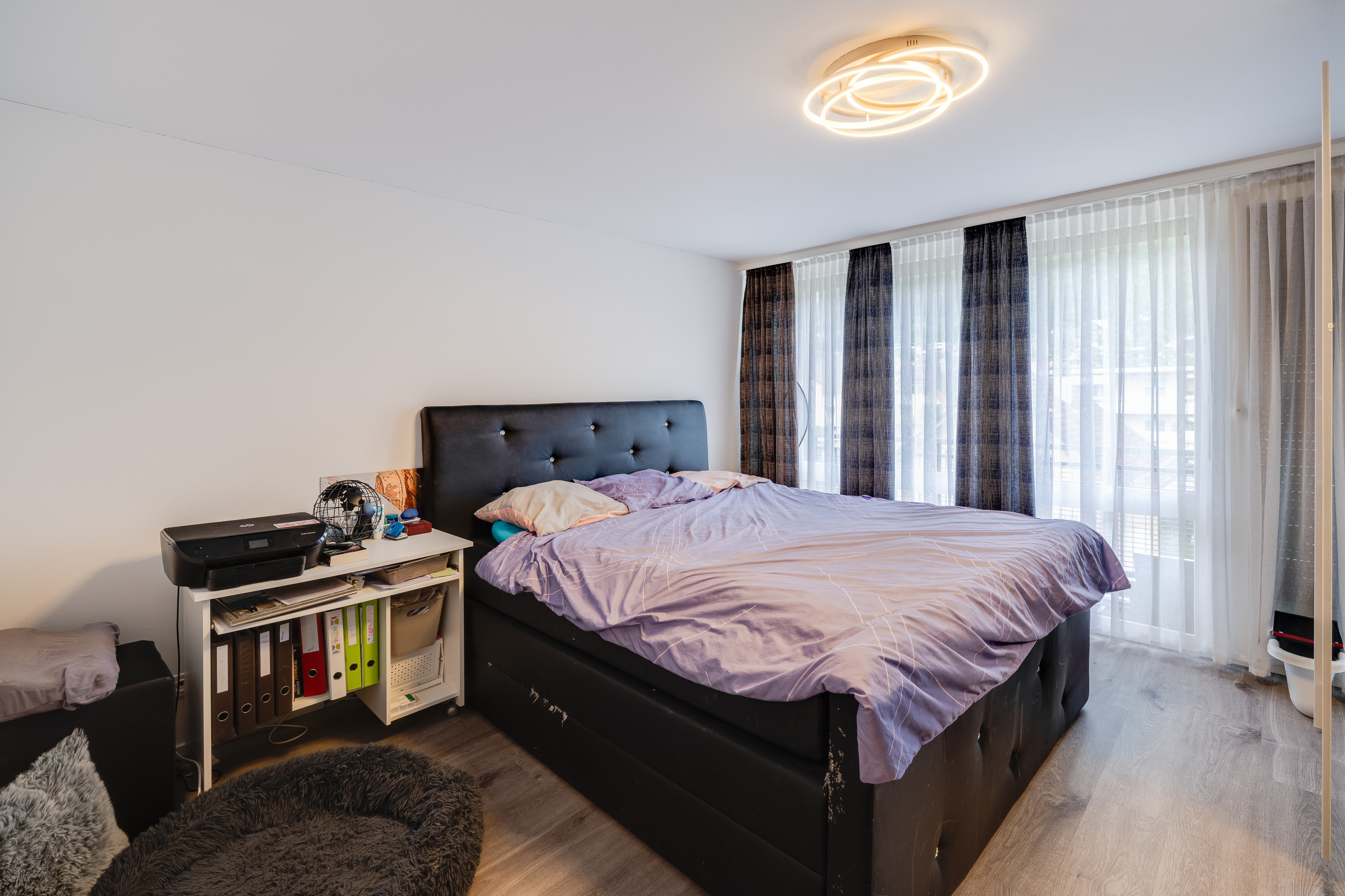 Schlafzimmer mit großem Bett und Fensterfront