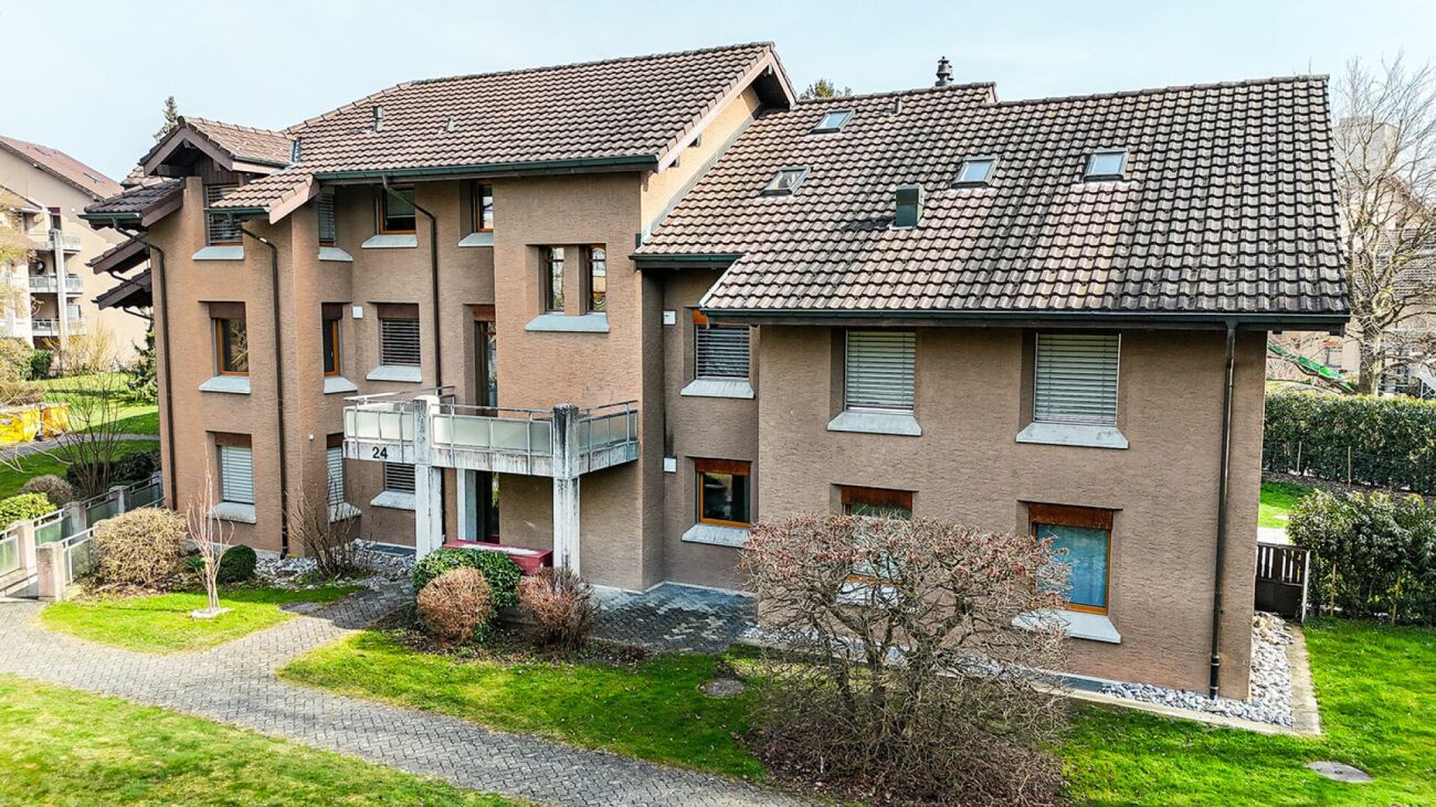 Mehrfamilienhaus mit Walmdach und umliegendem Garten