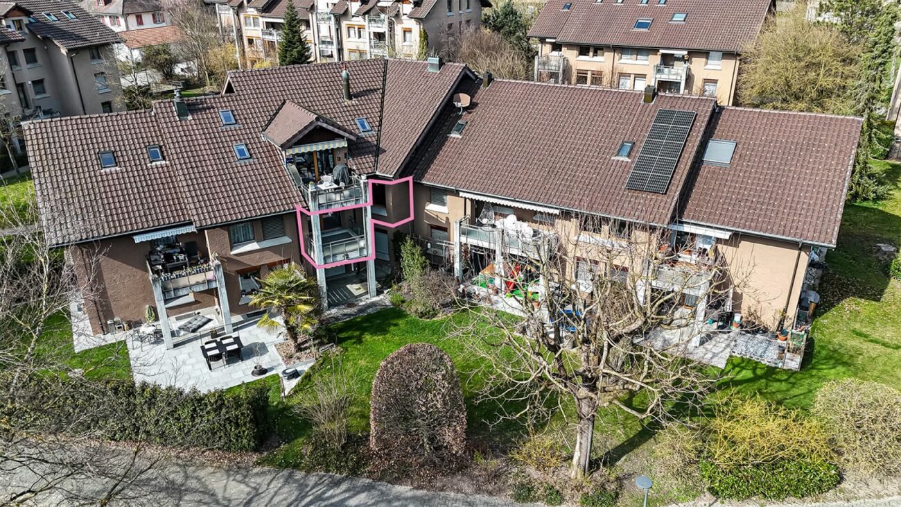 Luftaufnahme eines Mehrfamilienhauses mit Balkon und Garten