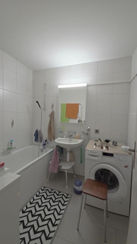 Kleines Badezimmer mit Badewanne und Waschmaschine