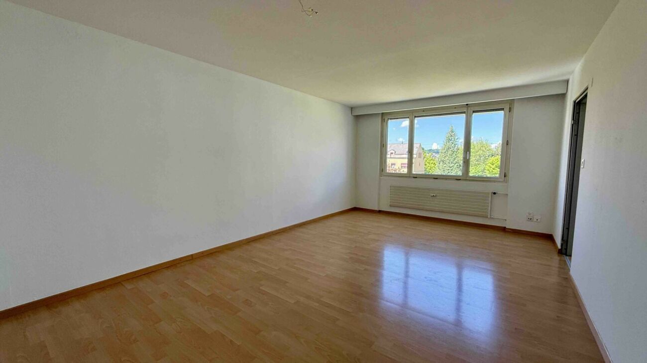 Leerer Wohnraum mit Holzfußboden und Fensterblick