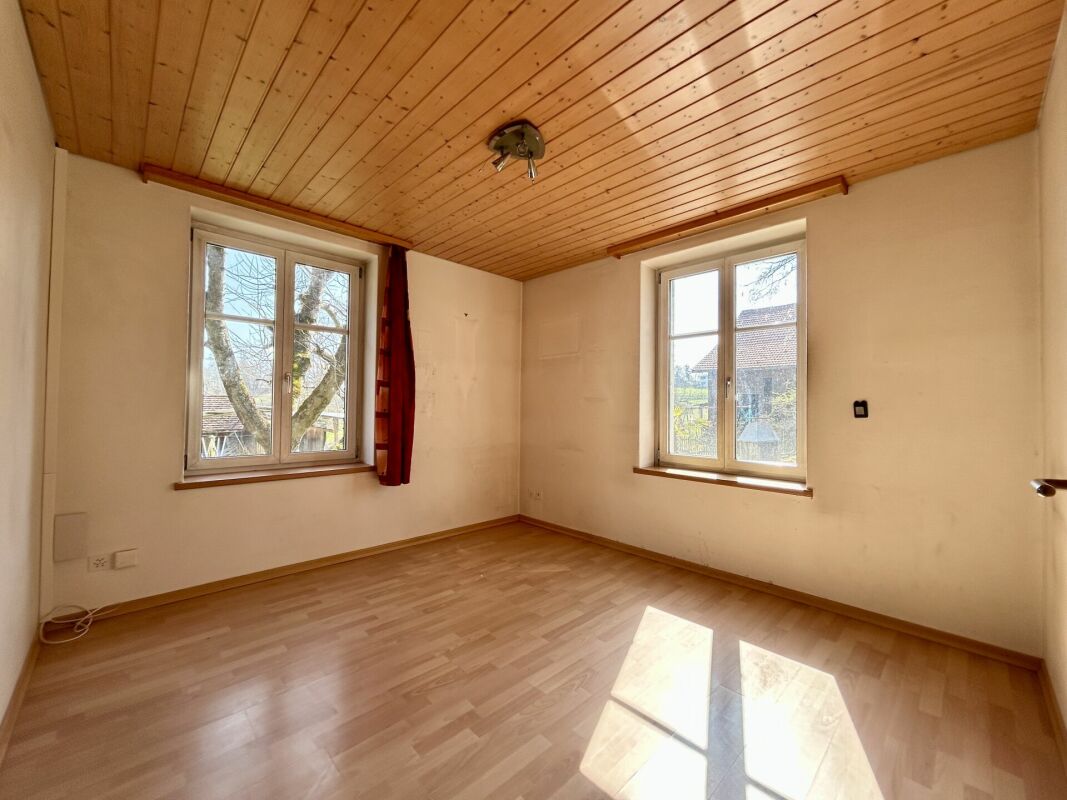 Leerer Raum mit Holzdecke und zwei Fenstern