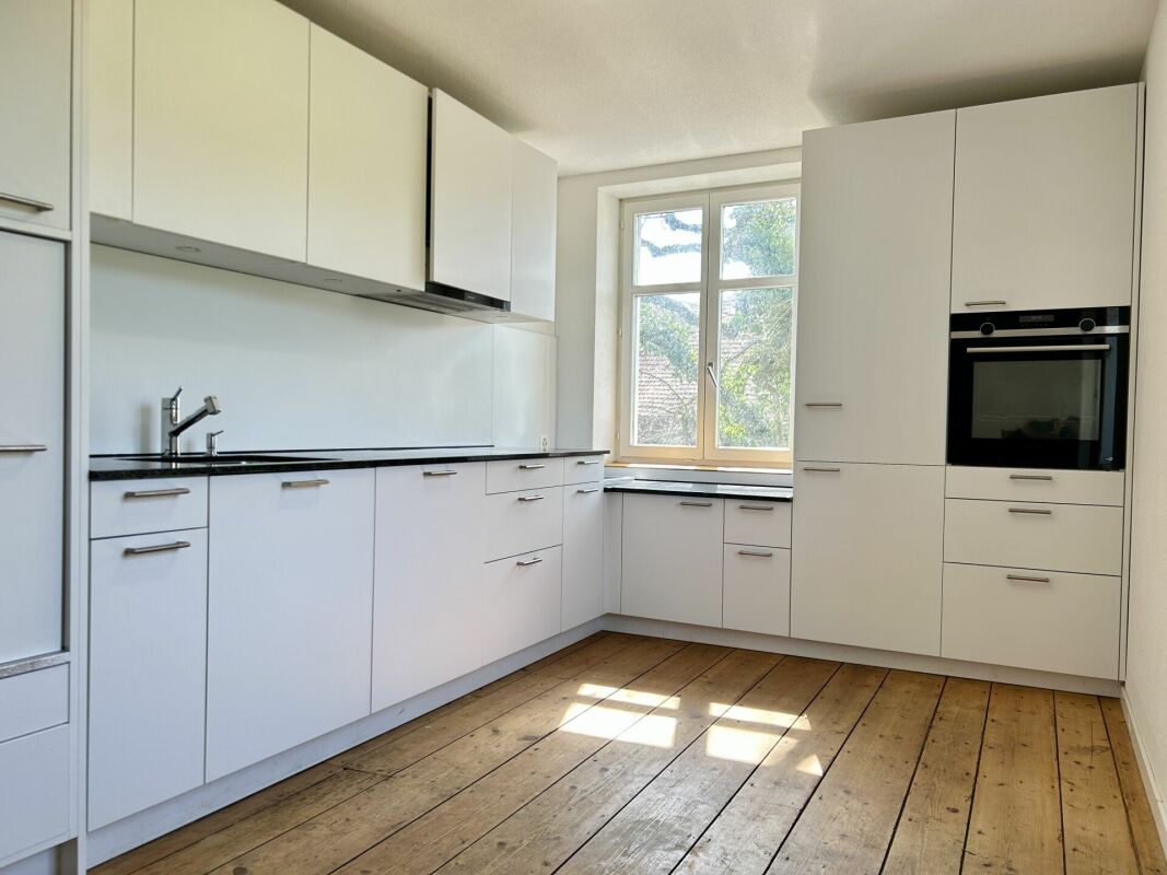 Helle, weiße Einbauküche mit Holzdielenboden