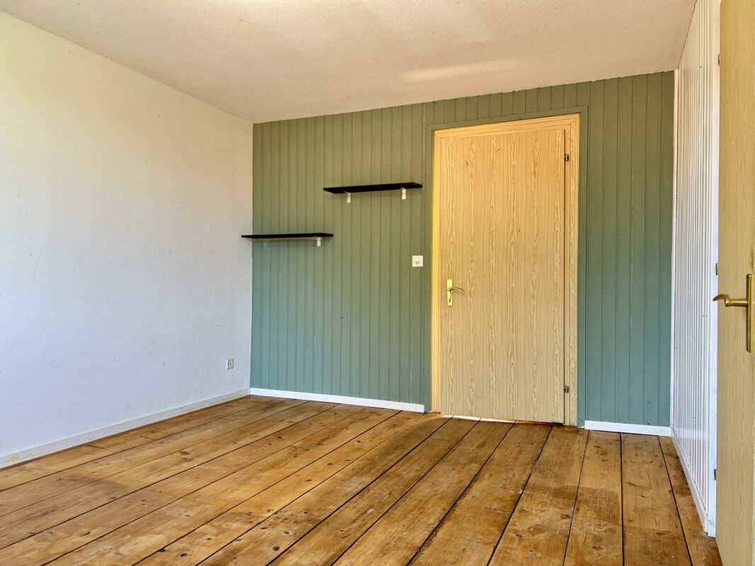 Leeres Zimmer mit Holzfußboden und grün akzentuierter Wand
