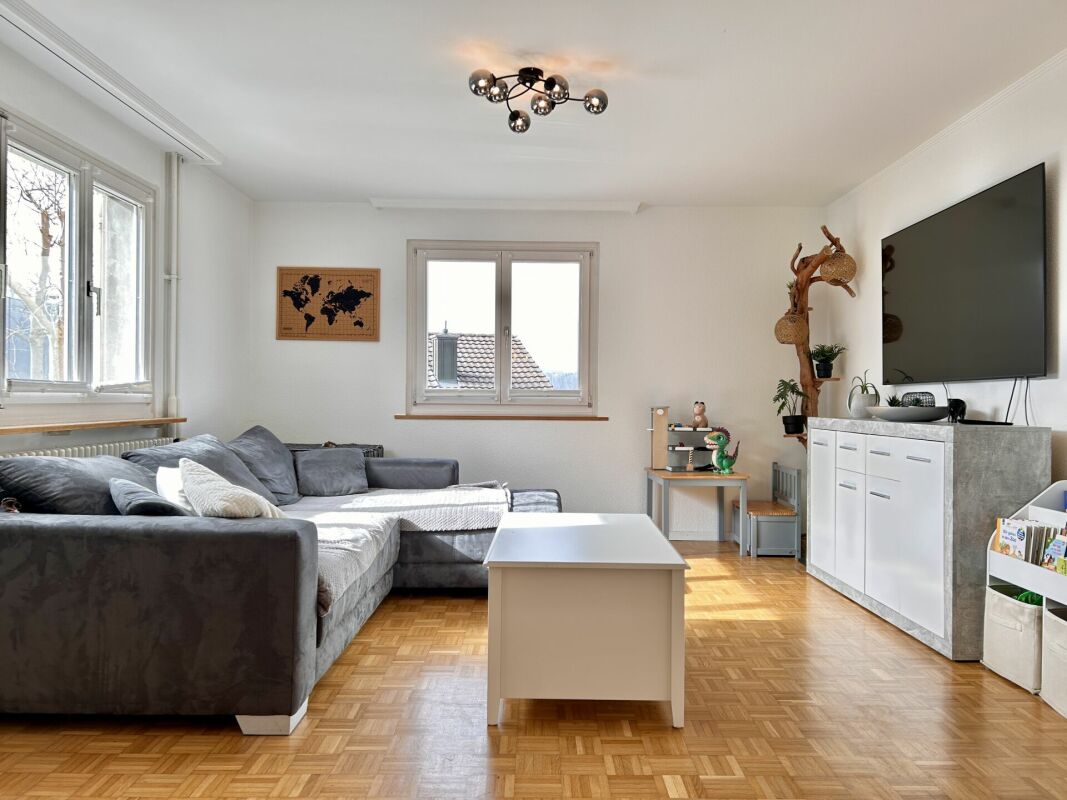 Helles Wohnzimmer mit grauer Eckcouch und TV