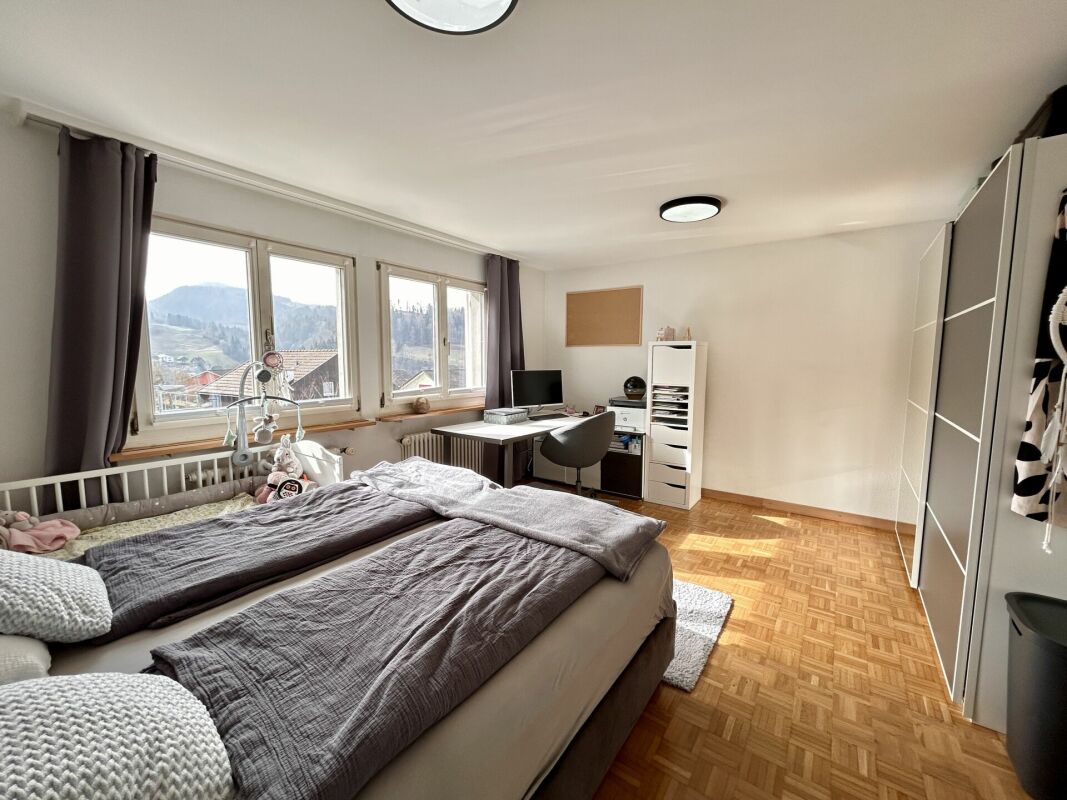 Helles Schlafzimmer mit Schreibtisch und Bergblick