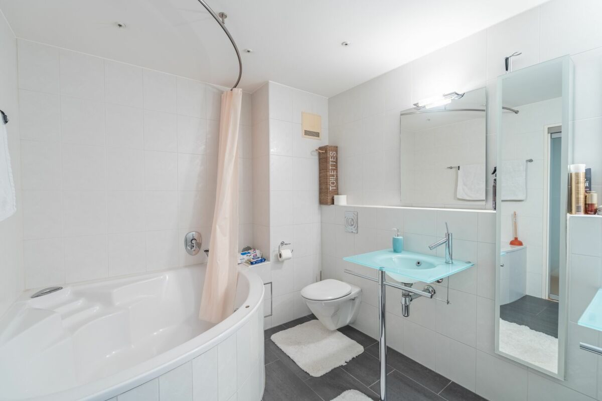 Modernes Badezimmer mit Wanne und Glaswaschtisch