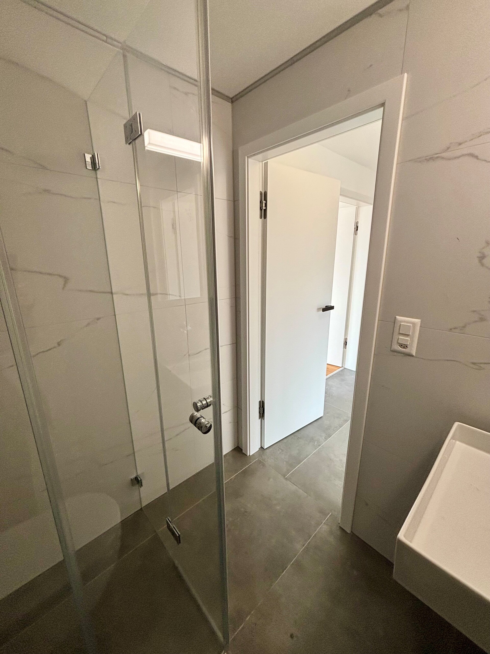 Modernes Badezimmer mit Glasdusche und Fliesen in Steinoptik