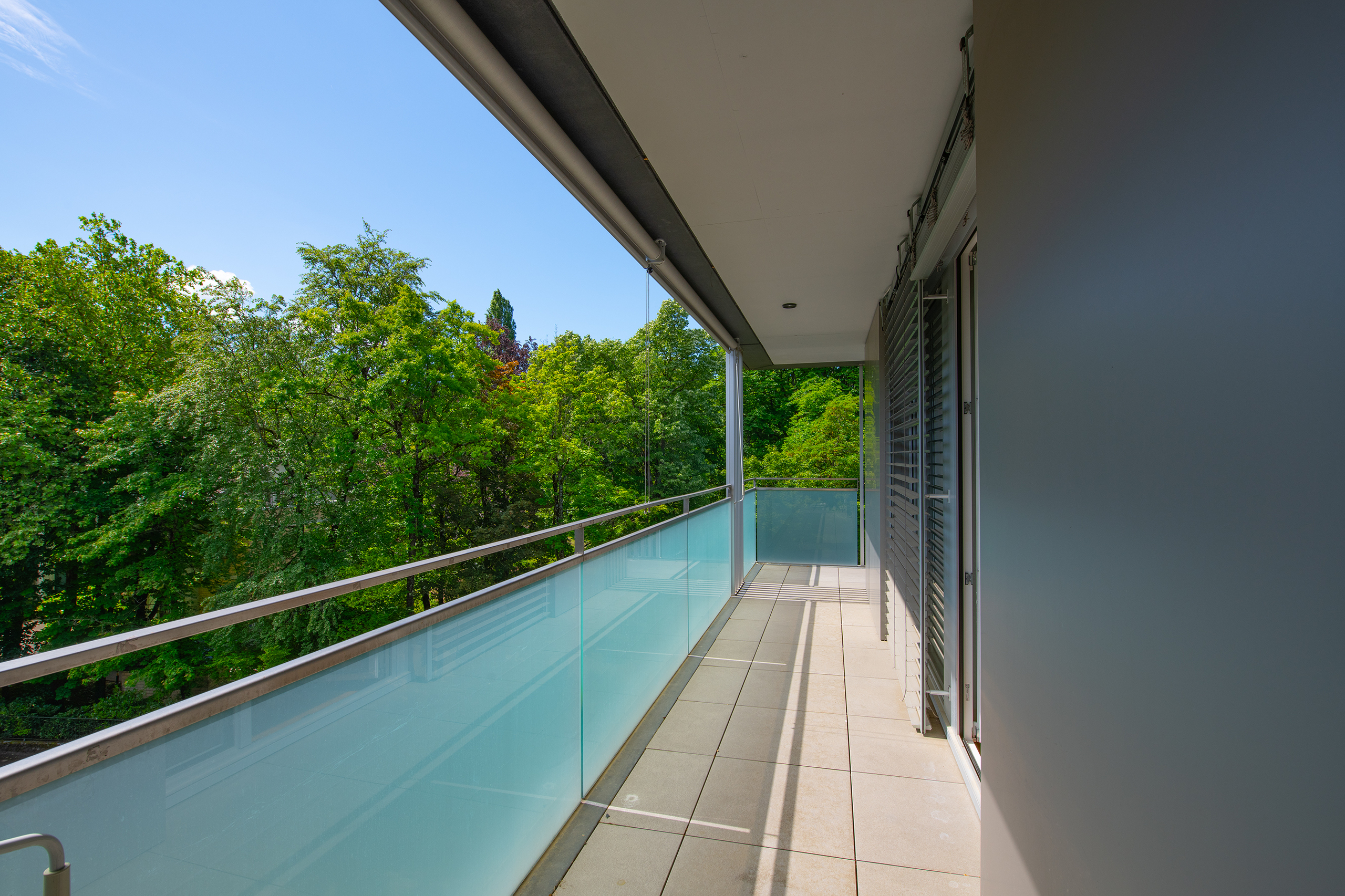 Balkon mit Glasgeländer und Grünblick