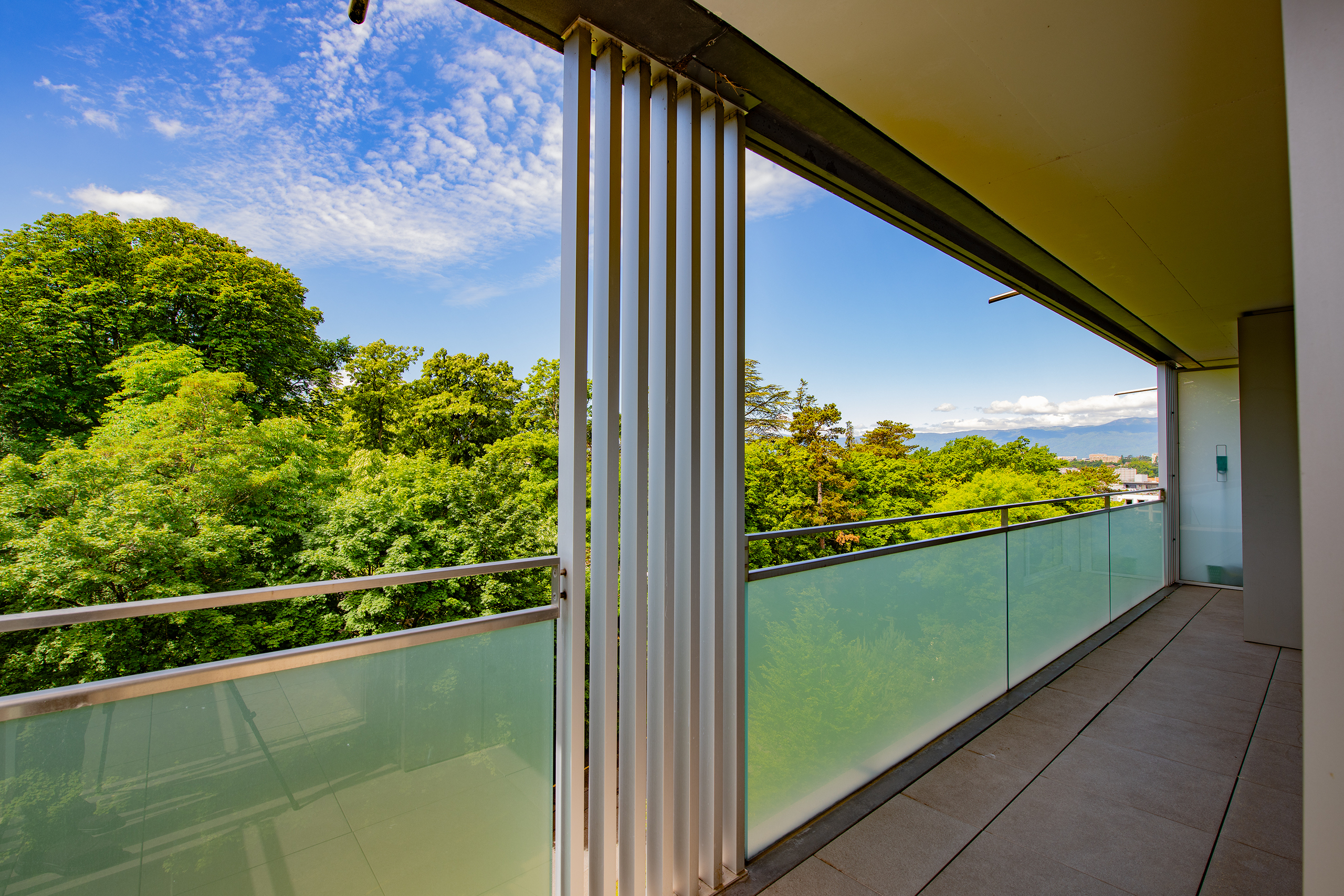 Balkon mit Glasgeländer und Grünblick