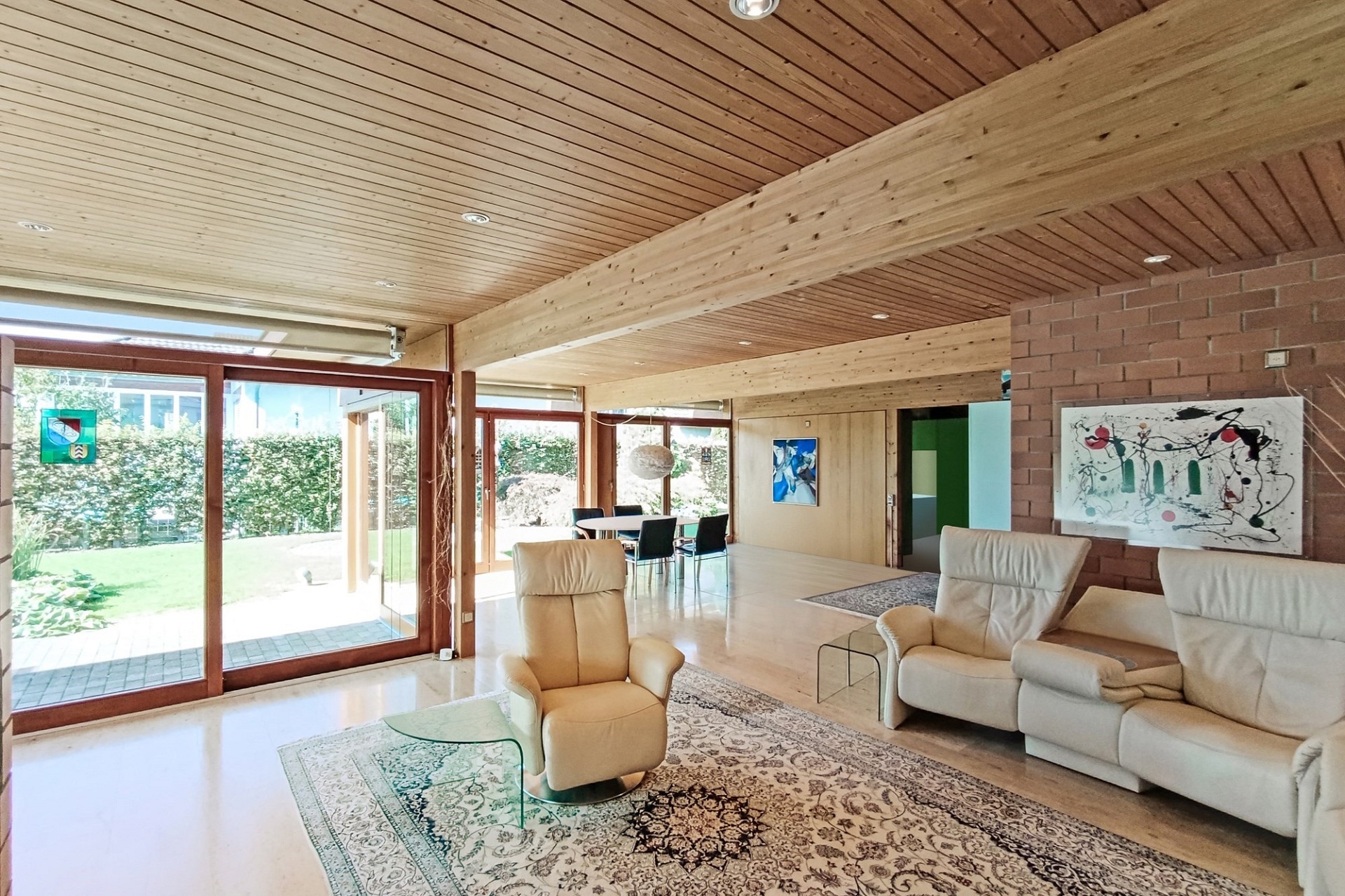 Großzügiges Wohnzimmer mit Holzdecke und Gartenblick