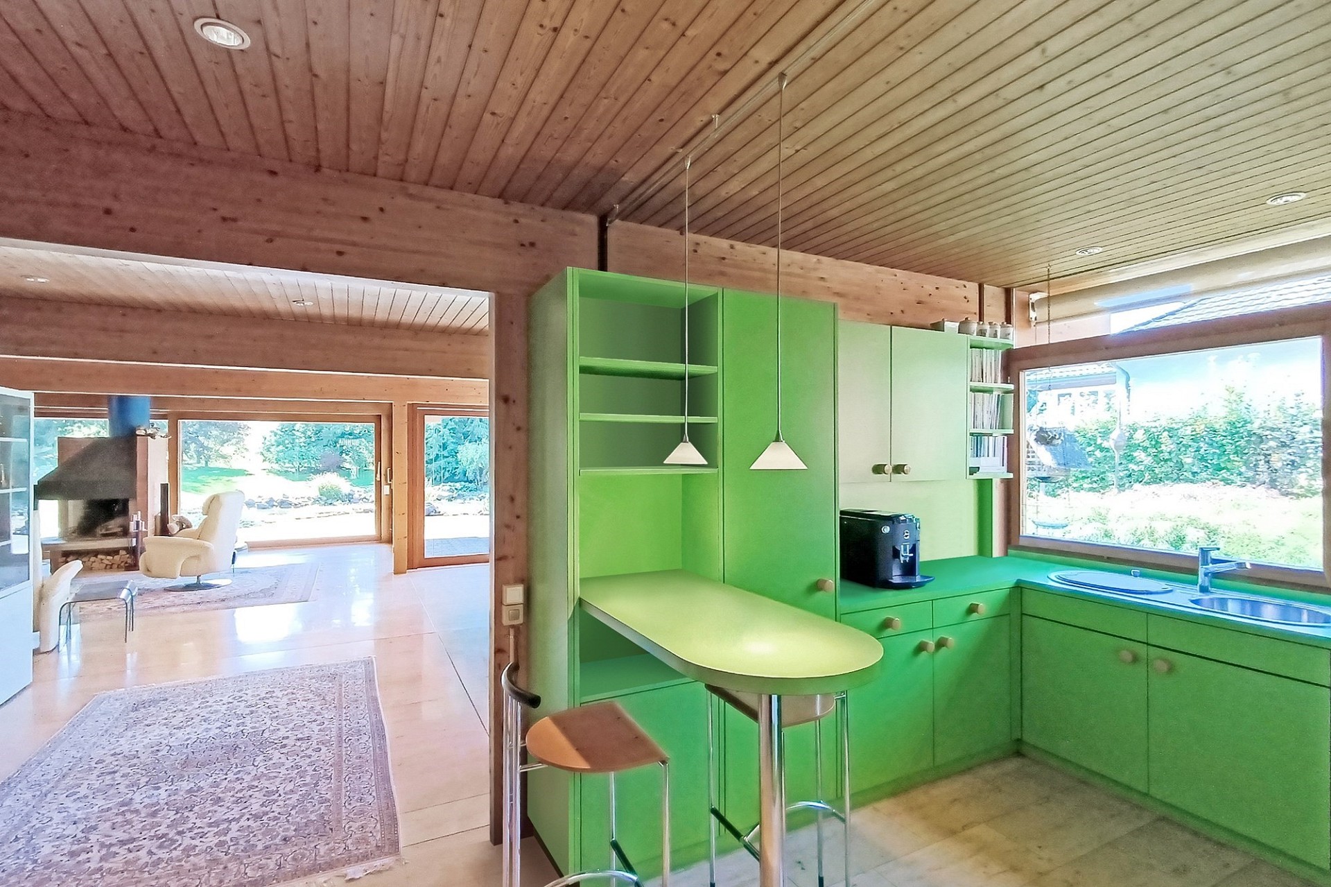 Offene Wohnküche mit Holzdecken und grünen Einbauten