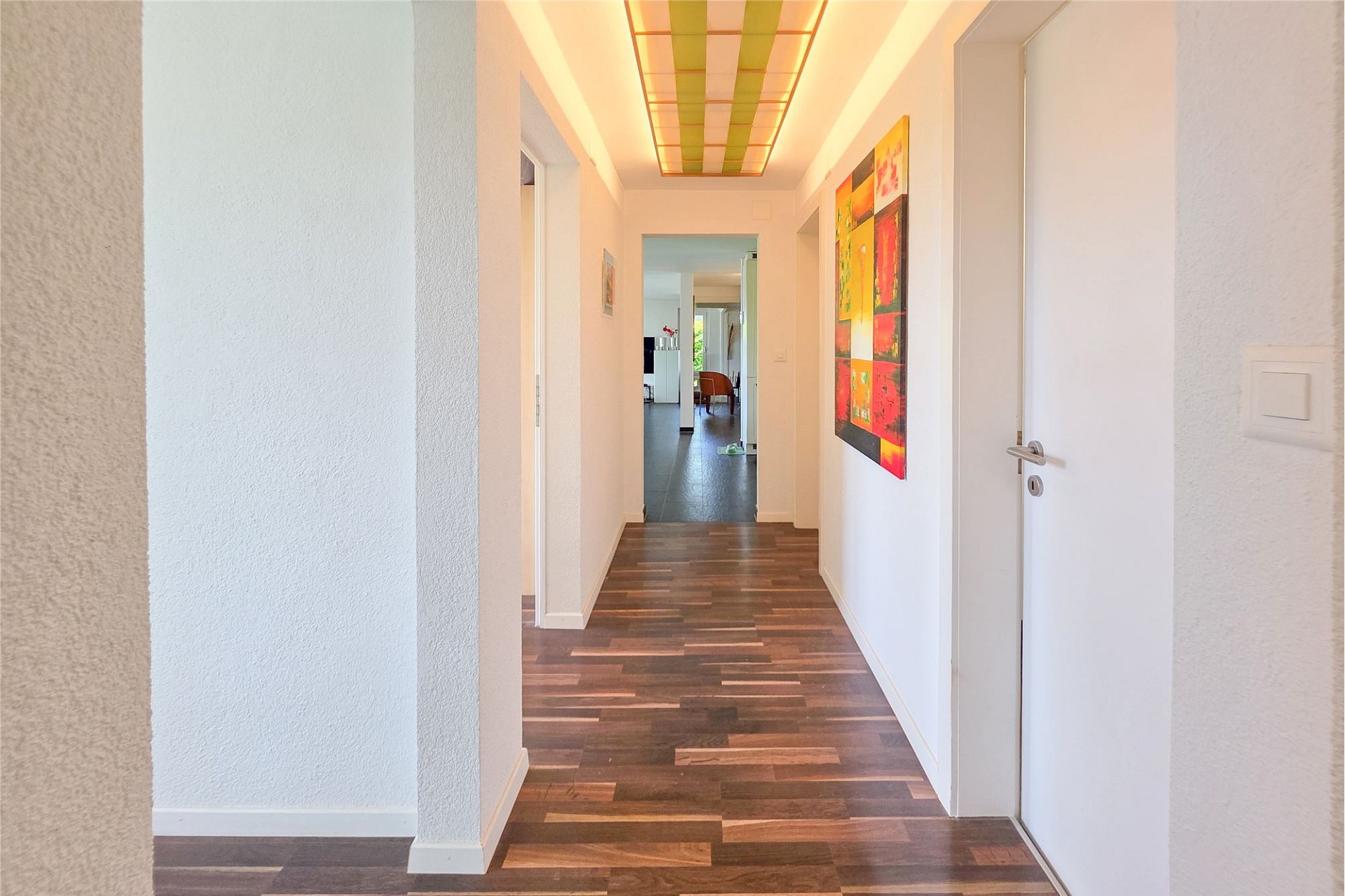 Heller Flur mit Holzoptik-Boden und farbigem Deckenpaneel