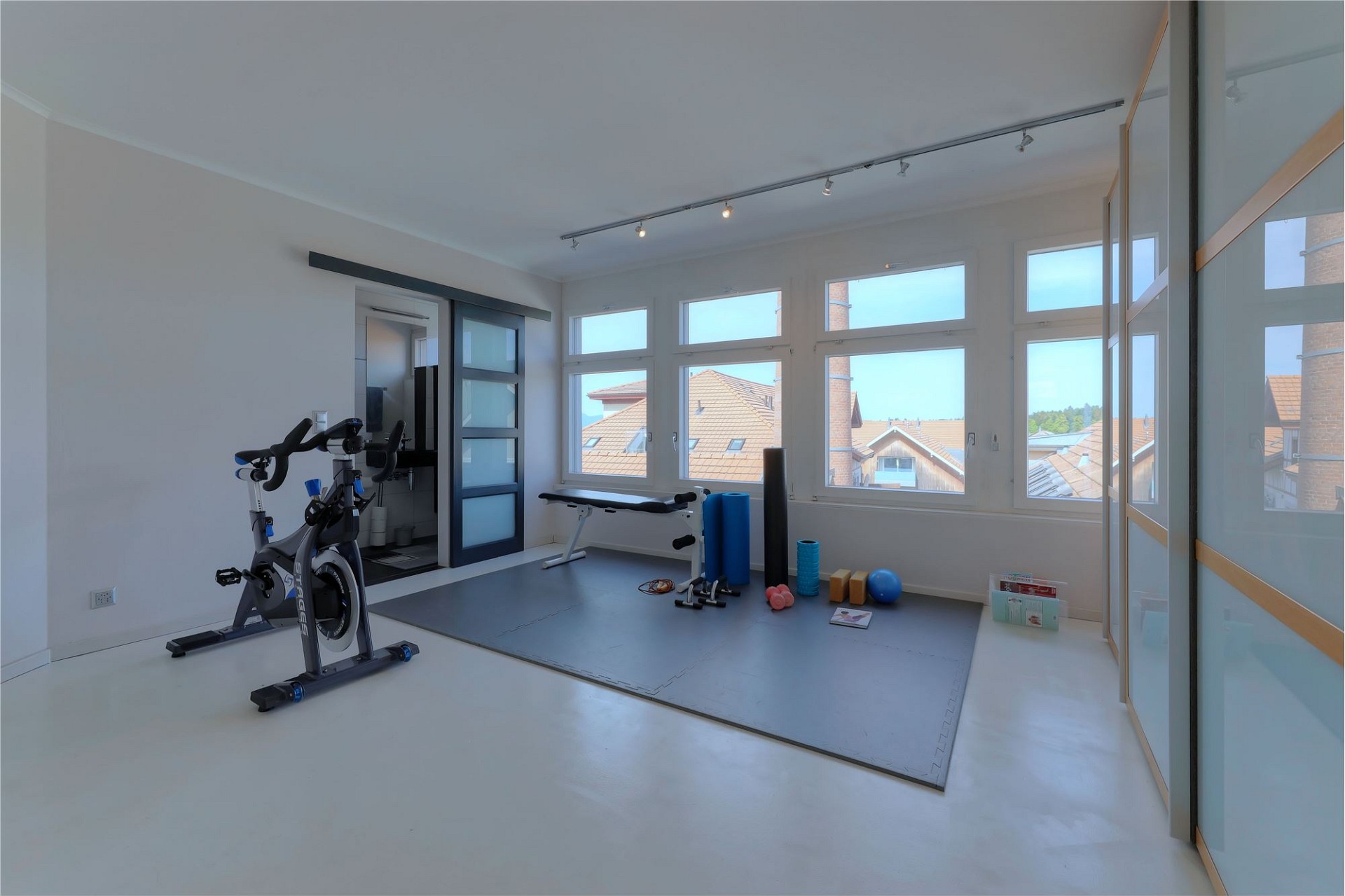 Heller Fitnessraum mit großen Fenstern