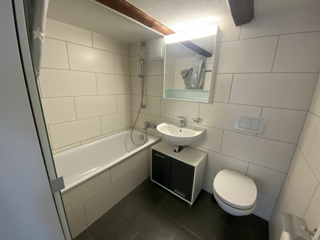 Kleines Badezimmer mit Wanne und Waschplatz