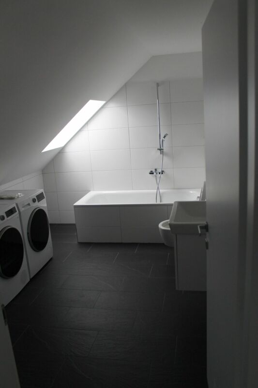 Badezimmer im Dachgeschoss mit Badewanne und Waschmaschinenbereich