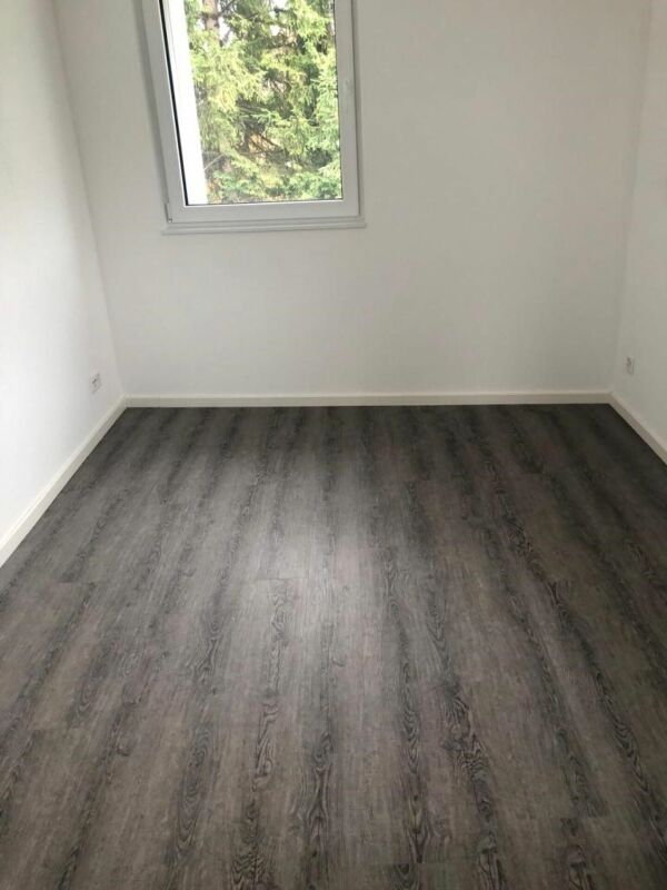 Leerer Raum mit Fenster und dunklem Bodenbelag