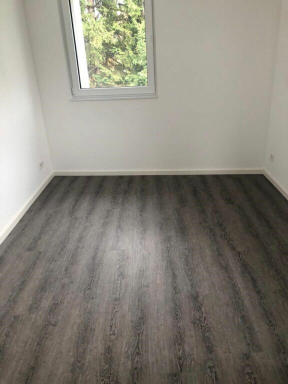 Leerer Raum mit Fenster und dunklem Boden