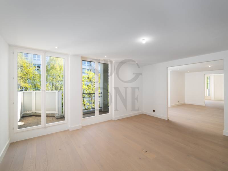 Heller, leerer Wohnraum mit Balkon und großem Durchgang