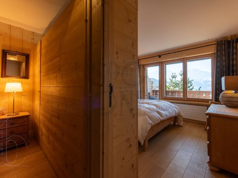 Gemütliches Schlafzimmer mit Holzverkleidung und Bergblick