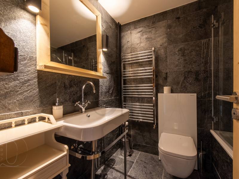 Kleines, dunkles Badezimmer mit Naturstein und WC