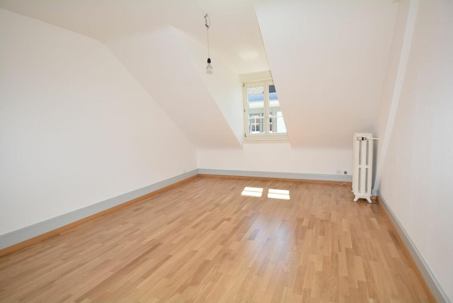 Leerer Dachraum mit Parkettboden und Dachfenster