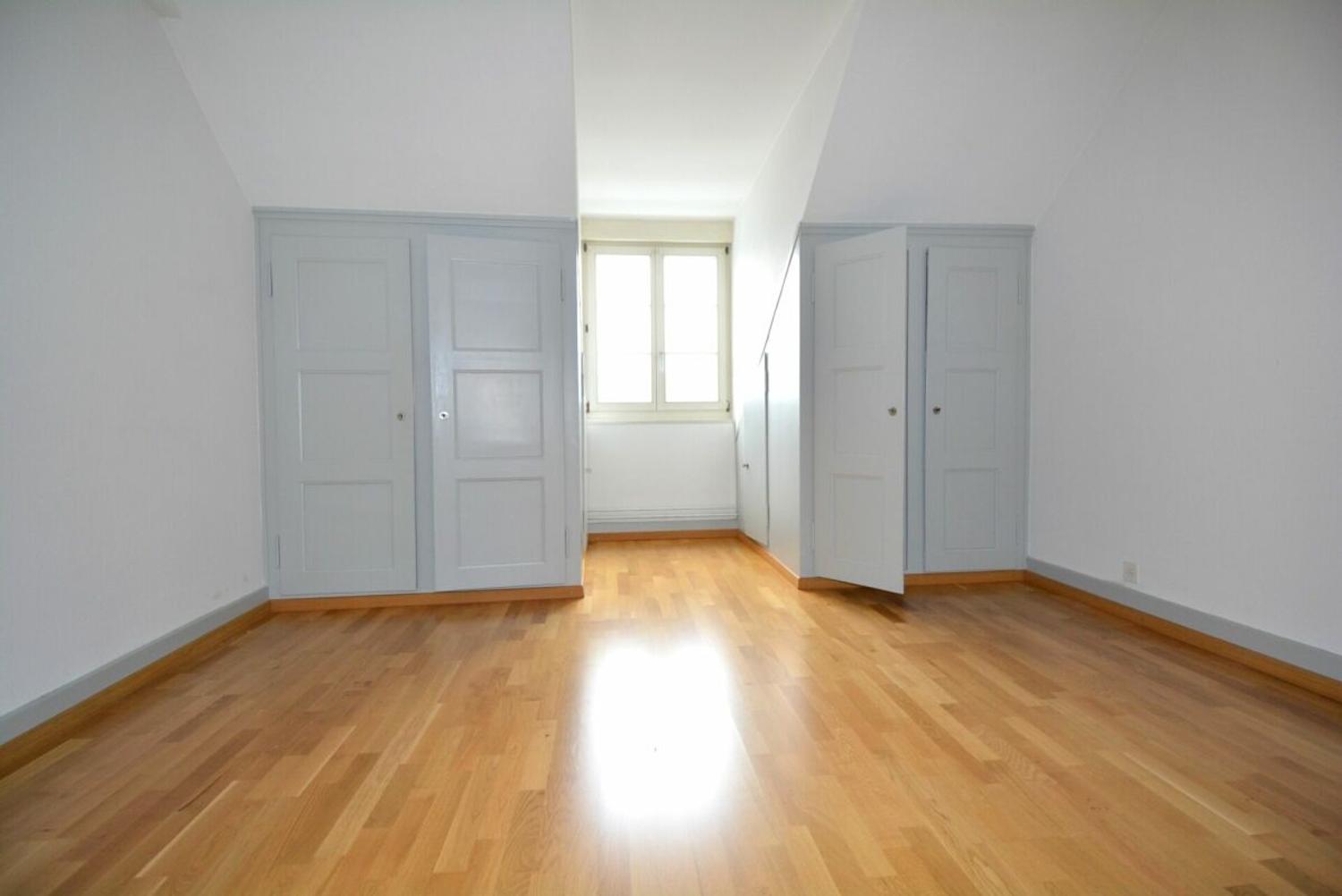 Helles, leeres Zimmer mit Holzboden und Einbauschränken