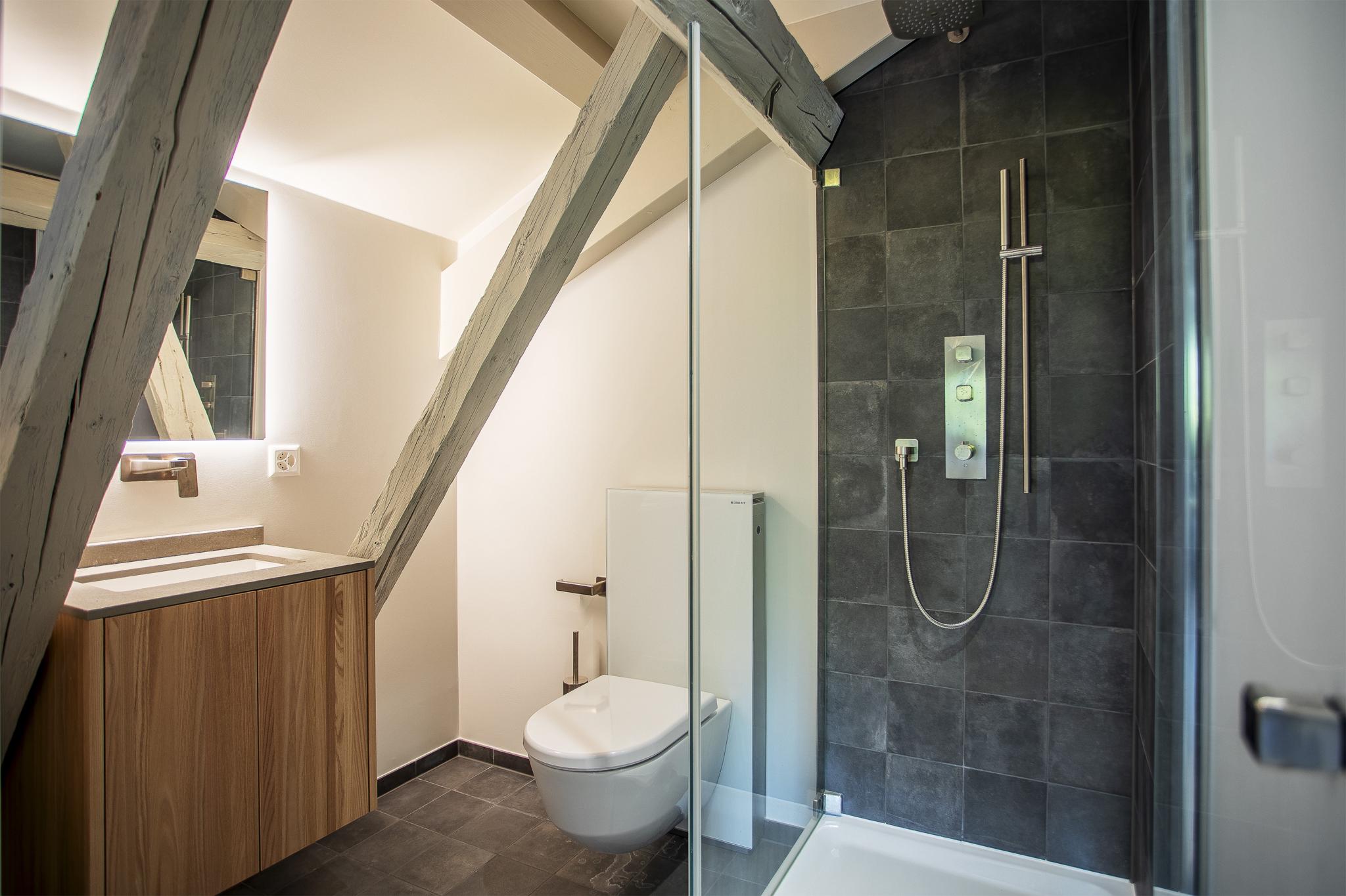 Modernes Bad mit Dusche und WC unter Dachbalken
