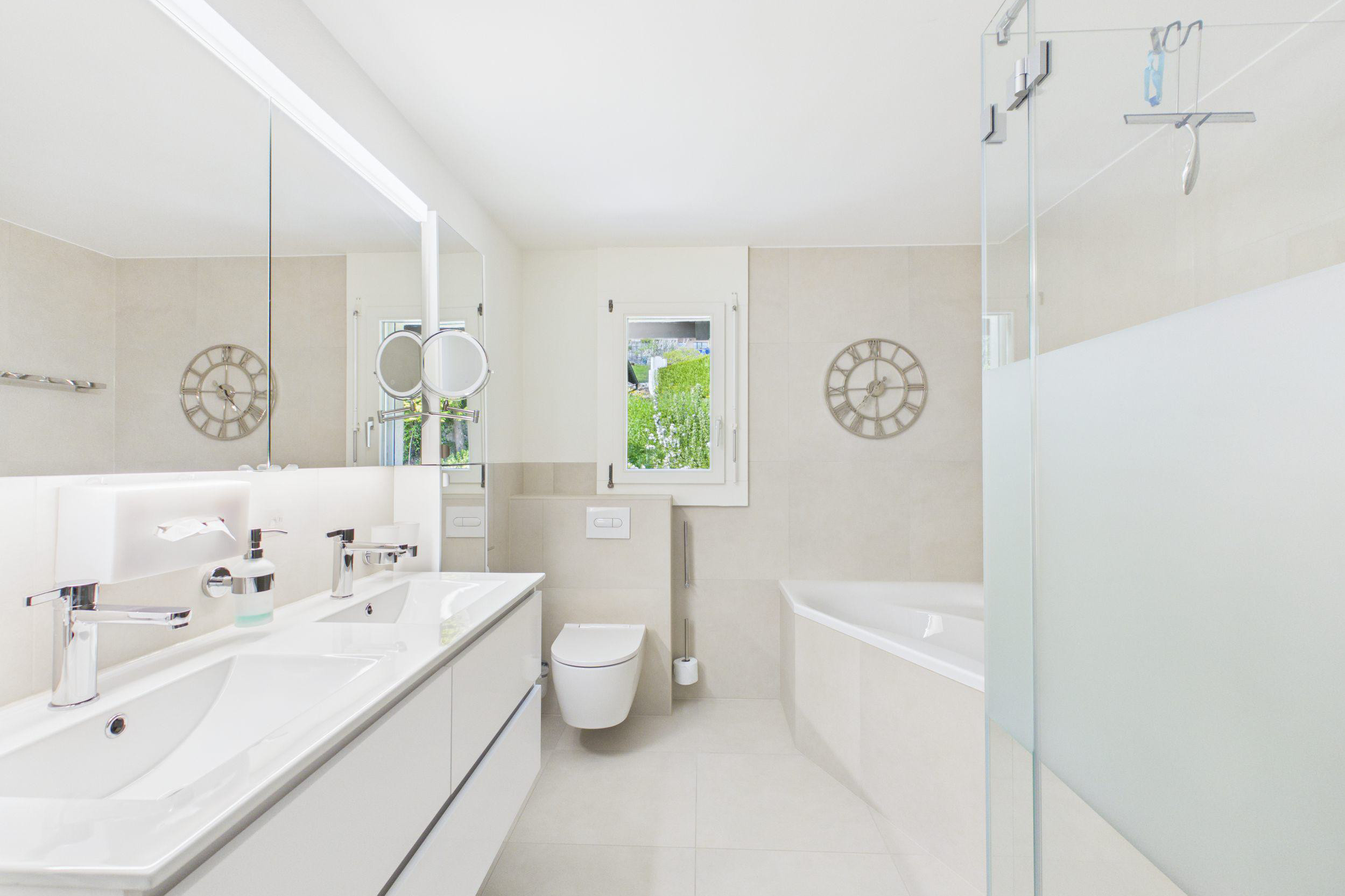Helles, modernes Badezimmer mit Doppelwaschtisch, WC und Badewanne