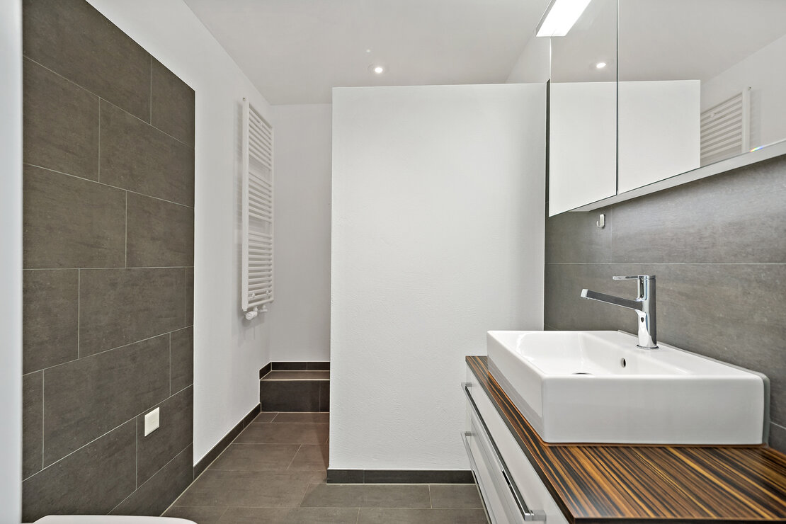 Modernes Badezimmer mit grauen Fliesen und Waschtisch