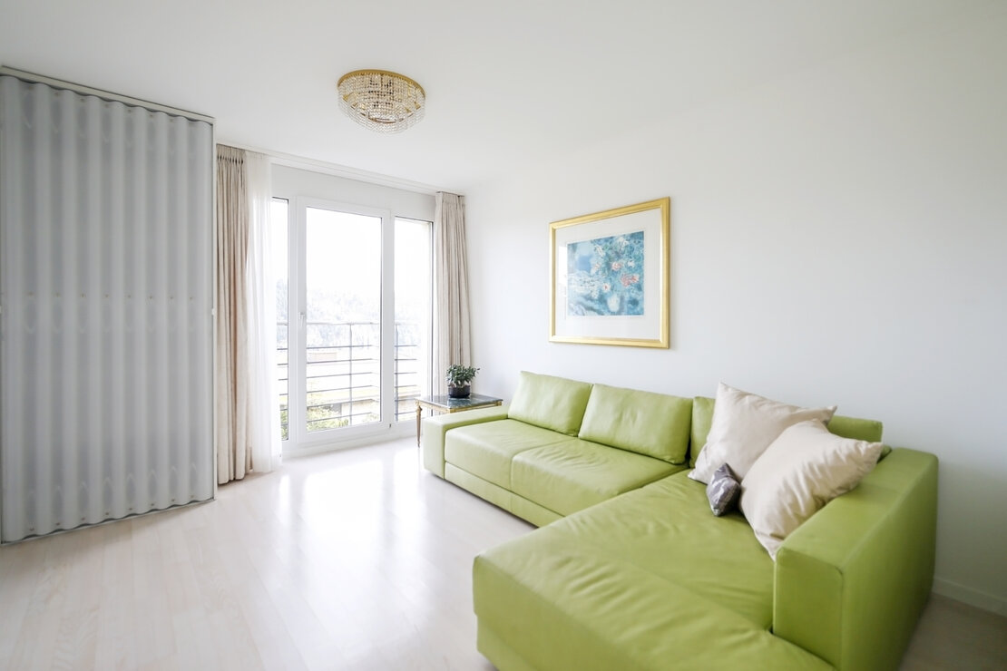 Helles Wohnzimmer mit grünem Ecksofa