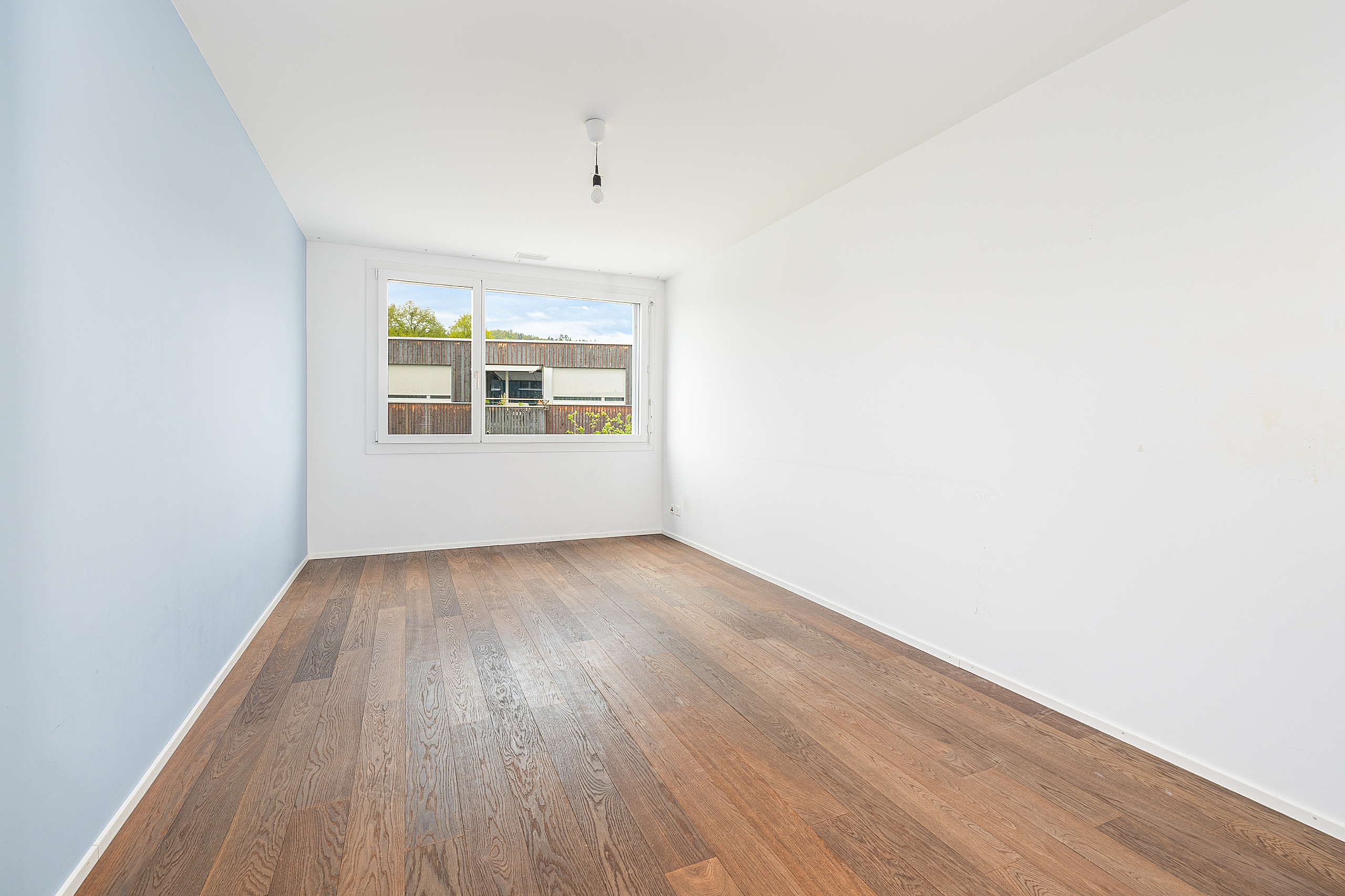 Helles, leeres Schlafzimmer mit Holzboden