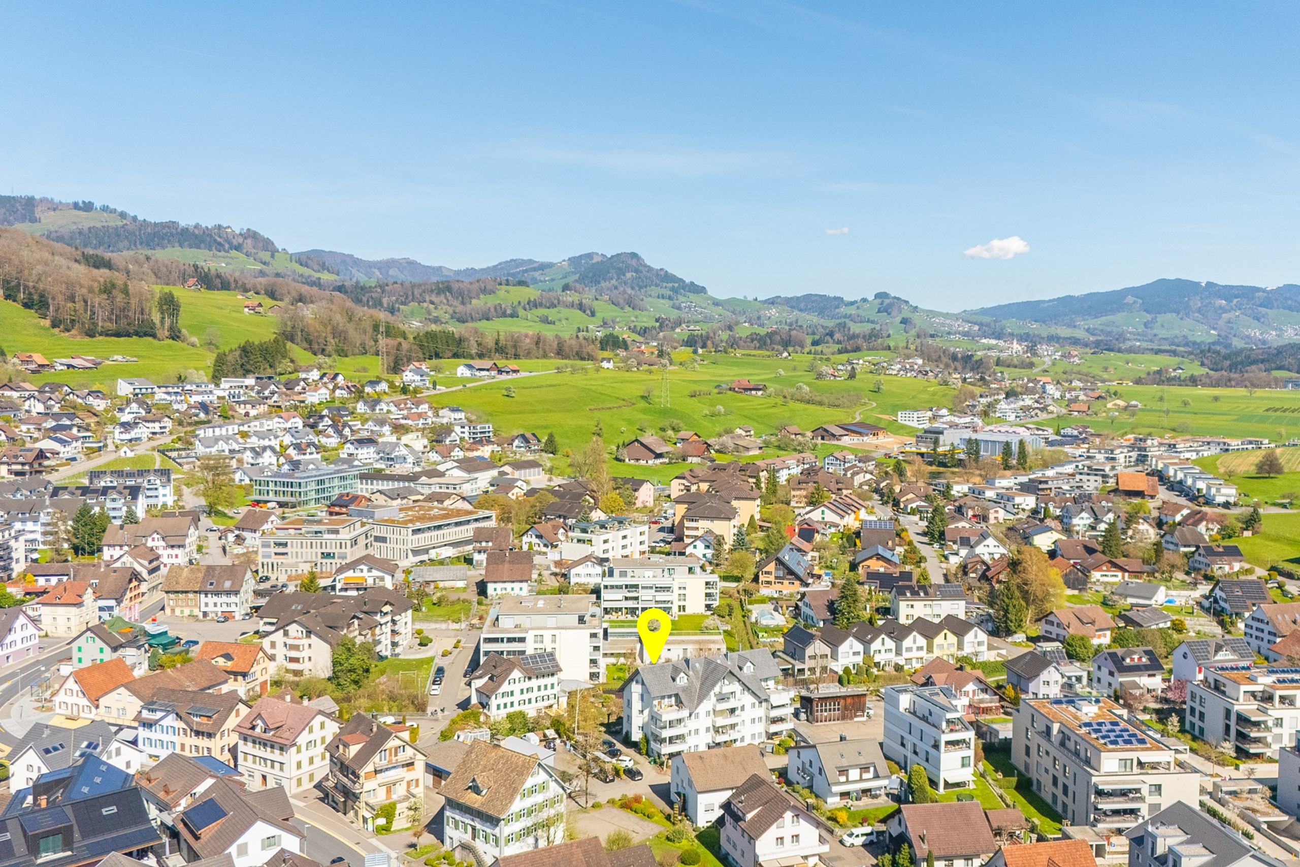 Luftaufnahme einer Stadt im Grünen mit Bergpanorama